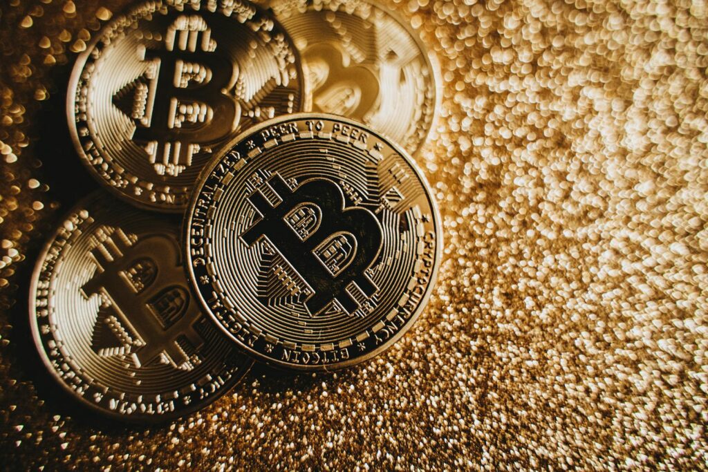 Close-up of Bitcoin cryptocurrency coins on a sparkling gold glitter background, symbolizing digital finance.