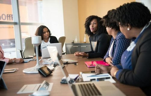 Diverse team of professionals engaging in a collaborative office meeting around a desk.