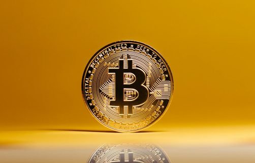 Golden Bitcoin coin showcased against a vibrant yellow background, symbolizing digital currency.