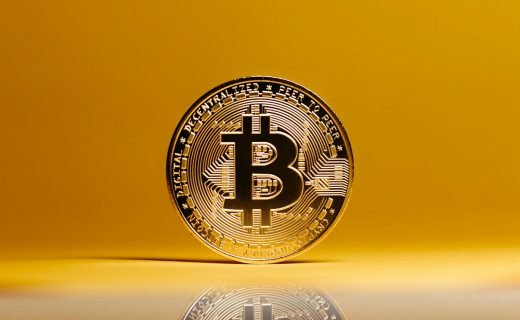 Golden Bitcoin coin showcased against a vibrant yellow background, symbolizing digital currency.