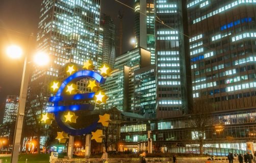 Night view of the iconic Euro sculpture in Frankfurt's bustling financial district.
