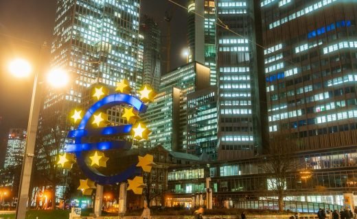 Night view of the iconic Euro sculpture in Frankfurt's bustling financial district.