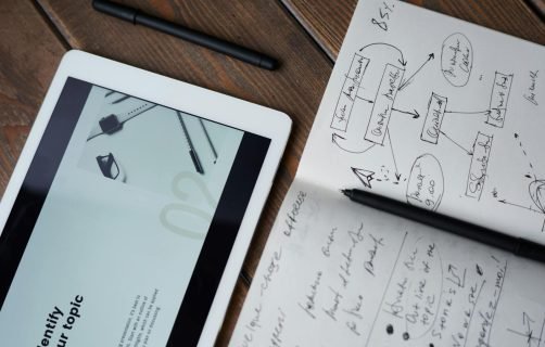 Digital and handwritten brainstorming tools on a wooden desk, ideal for business and study contexts.