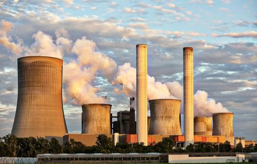 View of a power plant with smoke emissions under a cloudy sky, depicting industrial energy production.