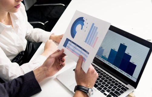 Business professionals discussing data charts and graphs in a modern office setting.