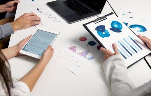 Team analyzing financial charts and digital reports during a business meeting.