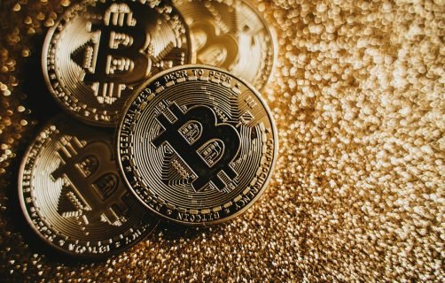 Close-up of Bitcoin cryptocurrency coins on a sparkling gold glitter background, symbolizing digital finance.