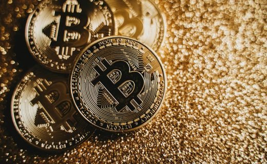 Close-up of Bitcoin cryptocurrency coins on a sparkling gold glitter background, symbolizing digital finance.