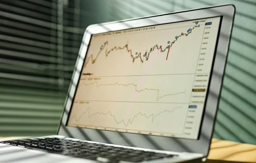 Close-up of a laptop displaying stock market data and graphs in an office setting.