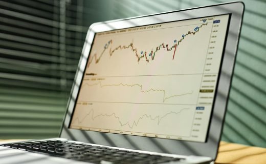 Close-up of a laptop displaying stock market data and graphs in an office setting.