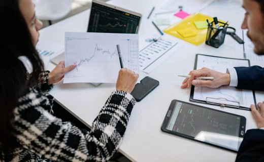 Two colleagues analyzing financial graphs during a business meeting in a modern office setting.
