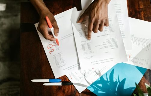 Overhead view of hands highlighting financial documents on a desk.