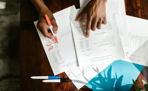 Overhead view of hands highlighting financial documents on a desk.