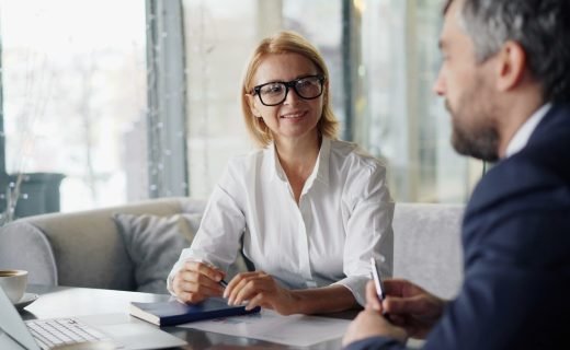 a man and woman sitting at a table with a laptop