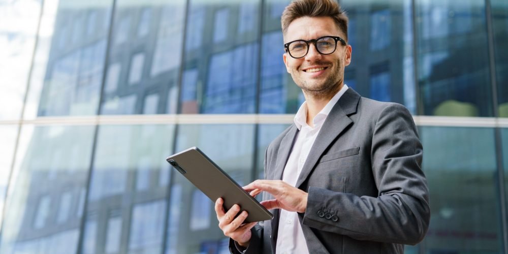 A,Cheerful,Businessman,In,A,Suit,Holds,A,Tablet,,Standing