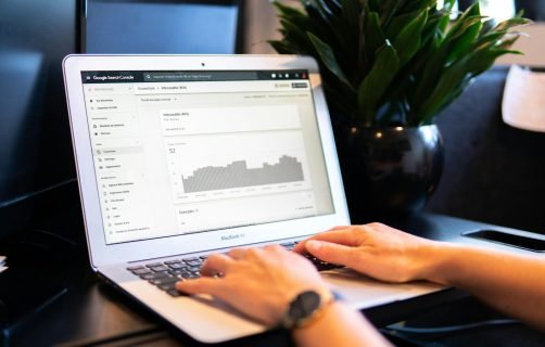 person using macbook air on brown wooden table