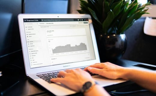 person using macbook air on brown wooden table