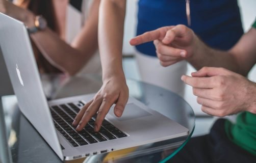 person touching and pointing MacBook Pro
