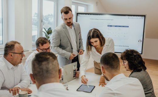 a group of people sitting around a table with laptops